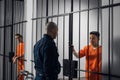 The prison warden puts the prisoner behind bars after the court verdict and locks the cell.