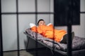 A prisoner in an asian high-security prison lies on a bunk in a red prisoner`s uniform in a solitary cell.
