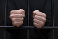 Prisoner holding hands in fists on courtroom bars, dark tone, selective focus. Royalty Free Stock Photo