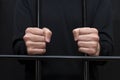 Prisoner holding hands in fists on courtroom bars, dark tone, selective focus. Royalty Free Stock Photo