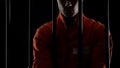 Prisoner in orange uniform standing behind bars, punishment for committed crime Royalty Free Stock Photo