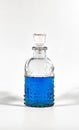 Pristine clear glass bottle containing a blue liquid isolated on a white backdrop