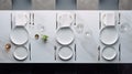 a pristine marble dining table, featuring neatly arranged white ceramic plates on stands, gleaming silverware, condiment