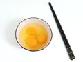 Pristine white bowl is filled with eggs and a pair of chopsticks resting atop a white table