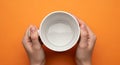 Pristine White Ceramic Mug Tilted by Two Hands Against Vibrant Orange Background Studio Mockup Royalty Free Stock Photo