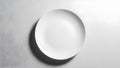 A pristine white dinner plate casts a soft shadow on a textured grey surface Royalty Free Stock Photo