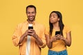 Privacy, distrust, infidelity. Suspicious black woman trying to look at her boyfriend's smartphone on yellow Royalty Free Stock Photo