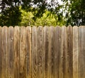 Weathered wood privacy fence with green shade tree background