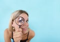 Private data and spying mockup. Curious young woman looking through a magnifying glass on color background. Copy space Royalty Free Stock Photo