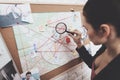 Private detective agency. Woman is looking at clue map with magnifying glass in office.