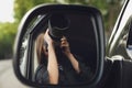 Private detective with camera spying from auto, view through car side mirror