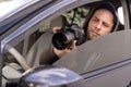 Private detective with camera spying from car, taking photo with professional camera