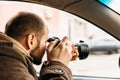 Private detective or reporter or paparazzi sitting in car and taking photo with professional camera Royalty Free Stock Photo