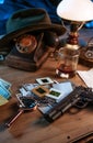 Private detective`s desk, noir still life with a vintage phone, typewriter, lamp, gun and retro photos Royalty Free Stock Photo