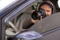 private detective sitting inside car taking picture with professional slr camera Royalty Free Stock Photo