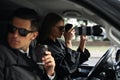 Private detectives with modern camera spying from car