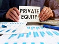 Private equity concept. Manager sitting at the table holds an inscription. Royalty Free Stock Photo