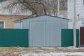 Gray iron garage and green metal fence in the street by the road Royalty Free Stock Photo