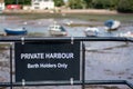 Private harbour berth holders only sign in black at a pretty harbor at low tide. Royalty Free Stock Photo