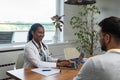 Private home doctor office female healthcare medical worker work with sick male patient. Ill young man talking with medic health Royalty Free Stock Photo