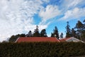 Private house roof with red tiles over green bushes with blue sky over Royalty Free Stock Photo