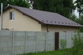 Private house with a tiled roof behind a gray concrete fence Royalty Free Stock Photo