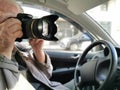 Private investigator with digital camera making photographs in car