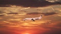 Private jet business plane comes in to land on background of beautiful sunset sky is orange with clouds and condensation traces Royalty Free Stock Photo