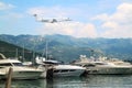 Private jet business plane flies low over yachts and boats in gulf of  background of mountains with white clouds Royalty Free Stock Photo