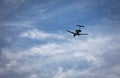 Private jet with landing gear down flying across blue sky with white cirrus clouds