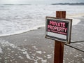 Private property no trespassing sign on pole and wire fence on beach property next to waves Royalty Free Stock Photo