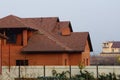 Private red brick house under a brown tiled roof behind a metal fence Royalty Free Stock Photo