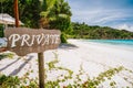 Private sign at tropical sandy beach with blue ocean lagoon in background at Mahe island, Seychelles