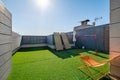 Private terrace with sunbeds, kids soccer gates and artificial turf on sunny day with blue sky.