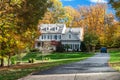 private two-storey house among autumn trees. Asphalt driveway to garage Royalty Free Stock Photo