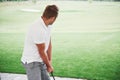 Pro golf player aiming shot with club on course. Male golfer on putting green about to take the shot, rear view Royalty Free Stock Photo