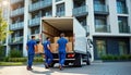 Pro movers unload boxes from truck into modern apartment building. Teamwork efficiently handles moving service. Urban setting. Royalty Free Stock Photo