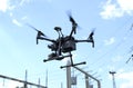 Pro quadcopter with camera aboard flying in a sky, electric pylon, cables and insulators on a background Royalty Free Stock Photo