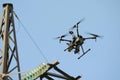 Pro quadcopter with camera aboard flying in a sky, electric pylon, cables and insulators on the background Royalty Free Stock Photo