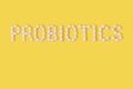 Probiotics word made of pills on yellow background. Flat lay, top view, free copy space.