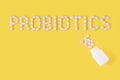 Probiotics word made of pills on yellow background. Flat lay, top view, free copy space.