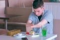 Disabled man with two amputated stump hands eats sushi rolls in cafe with fork.