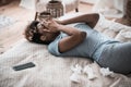 Darkskinned woman covering face with hands lying on bed