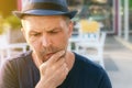 A problem middle-aged man in a blue hat is thinking and thinking. maybe he has a toothache. close-up portrait Royalty Free Stock Photo