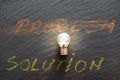 Problem and solution written with chalk on black stone texture, and a small light bulb Royalty Free Stock Photo