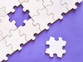 One piece jigsaw puzzle next to connected pieces against purple background. Royalty Free Stock Photo