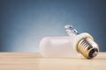 Broken light bulb on wooden desk over gently lit dark background Royalty Free Stock Photo