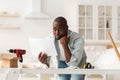 Problems with new furniture assembly. Shocked african american man reading instructions at home Royalty Free Stock Photo