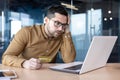 Problems with payment, credit card transaction. A young man sits in the office in front of a laptop monitor and Royalty Free Stock Photo