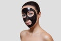 The procedure for applying a black mask to the face of a beautiful woman.